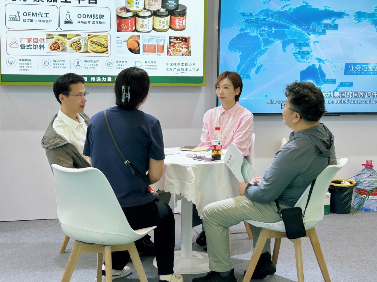 People in conversation at a table in the Senyo exhibition booth.
